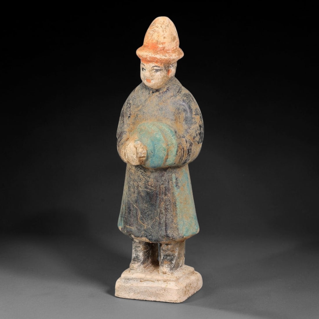 A Chinese Ming Dynasty Glazed Terracotta Male Attendant Figurine, 79AL: Modelled in hollow terracotta, the standing male attendant retains polychrome pigment and glaze. The figure wears a tall conical hat with reddish pigment at the brim, and defined facial features with 