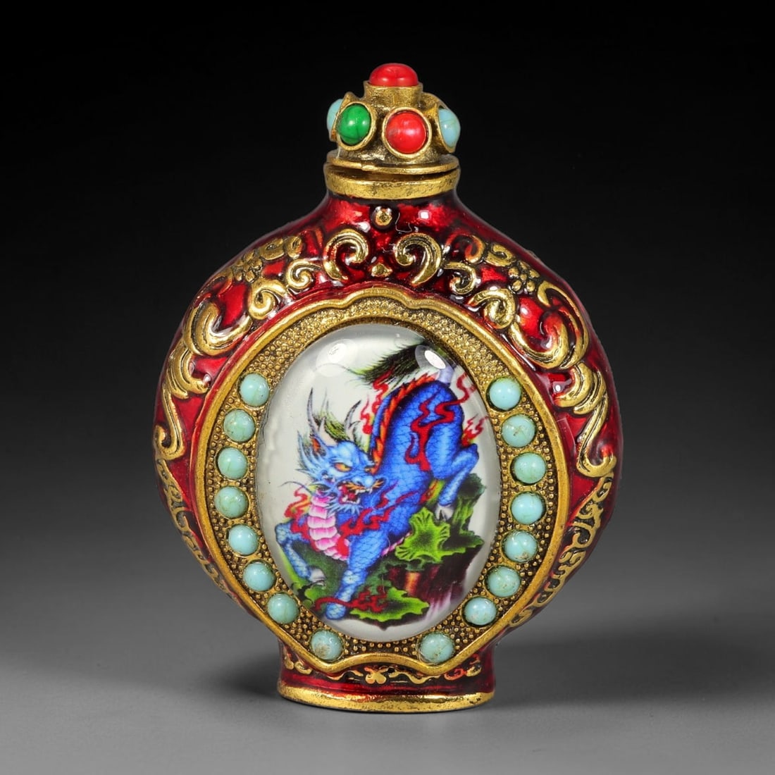 A Chinese Copper Alloy Inset Painted Panel Snuff Bottle, 37AV: Modelled in copper alloy with red enamel and gilt decoration, the snuff bottle has a flattened circular form with ornate gilt scrollwork in relief across the body. Each side features an oval inset pai