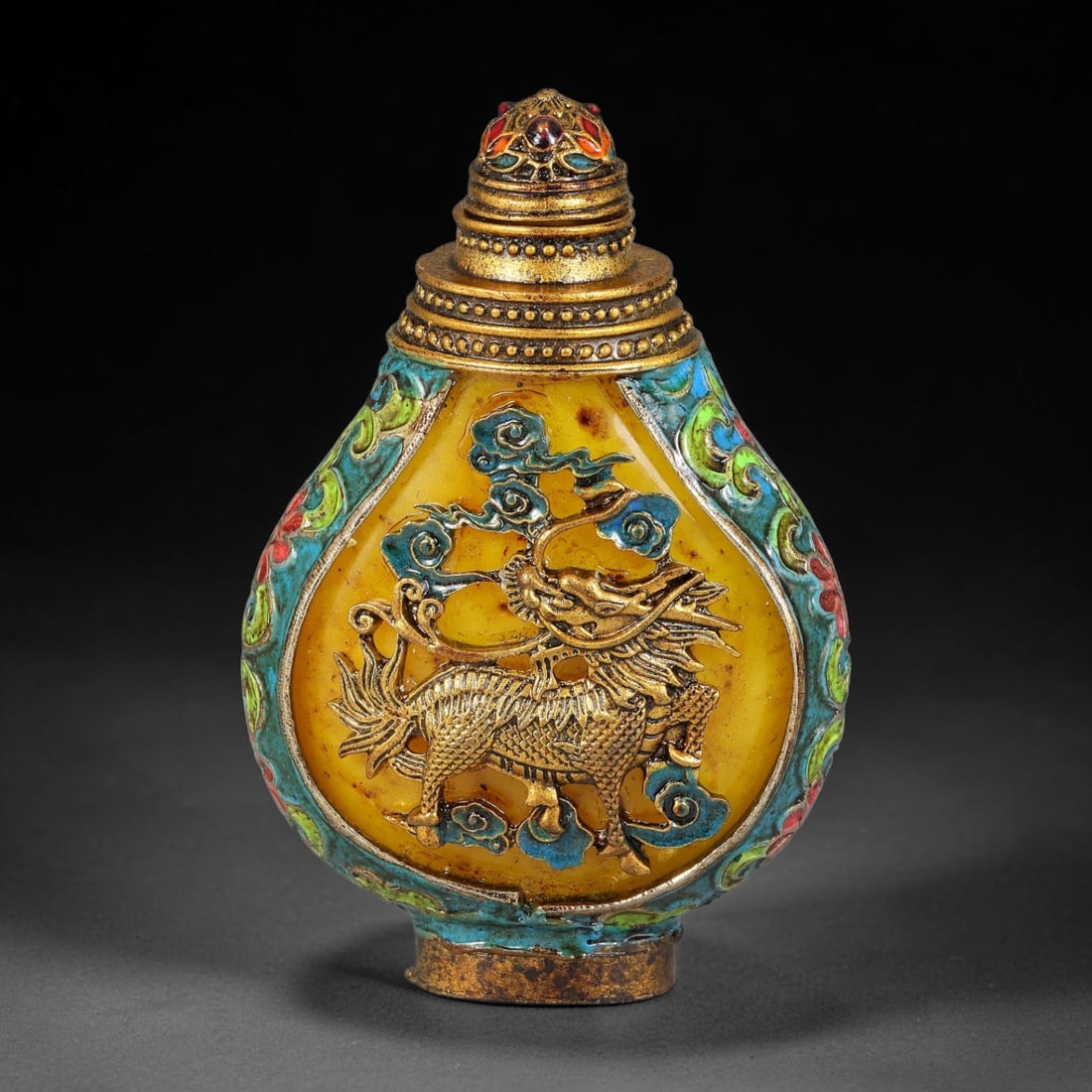 A Chinese Gilt Metal Enamel Overlay Snuff Bottle with Qilin Motif, 39AV: Pear-shaped snuff bottle constructed with a yellow ground panel, fitted with a multi-tiered gilt stopper accented with coloured enamel. The central face bears raised gilt relief depicting a qilin amid