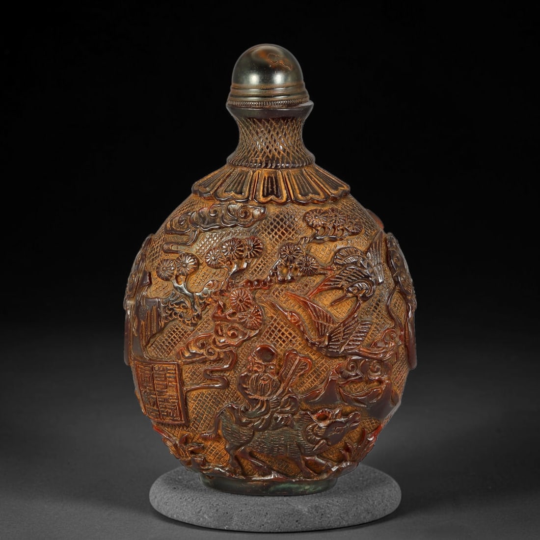 A Chinese Amber Resin Deep Relief Carved Snuff Bottle, 68AV: Large ovoid snuff bottle crafted from amber resin, intricately carved in deep relief on both sides. One side depicts a figure mounted upon an ox amid pine trees, cranes and swirling cloud motifs, the 