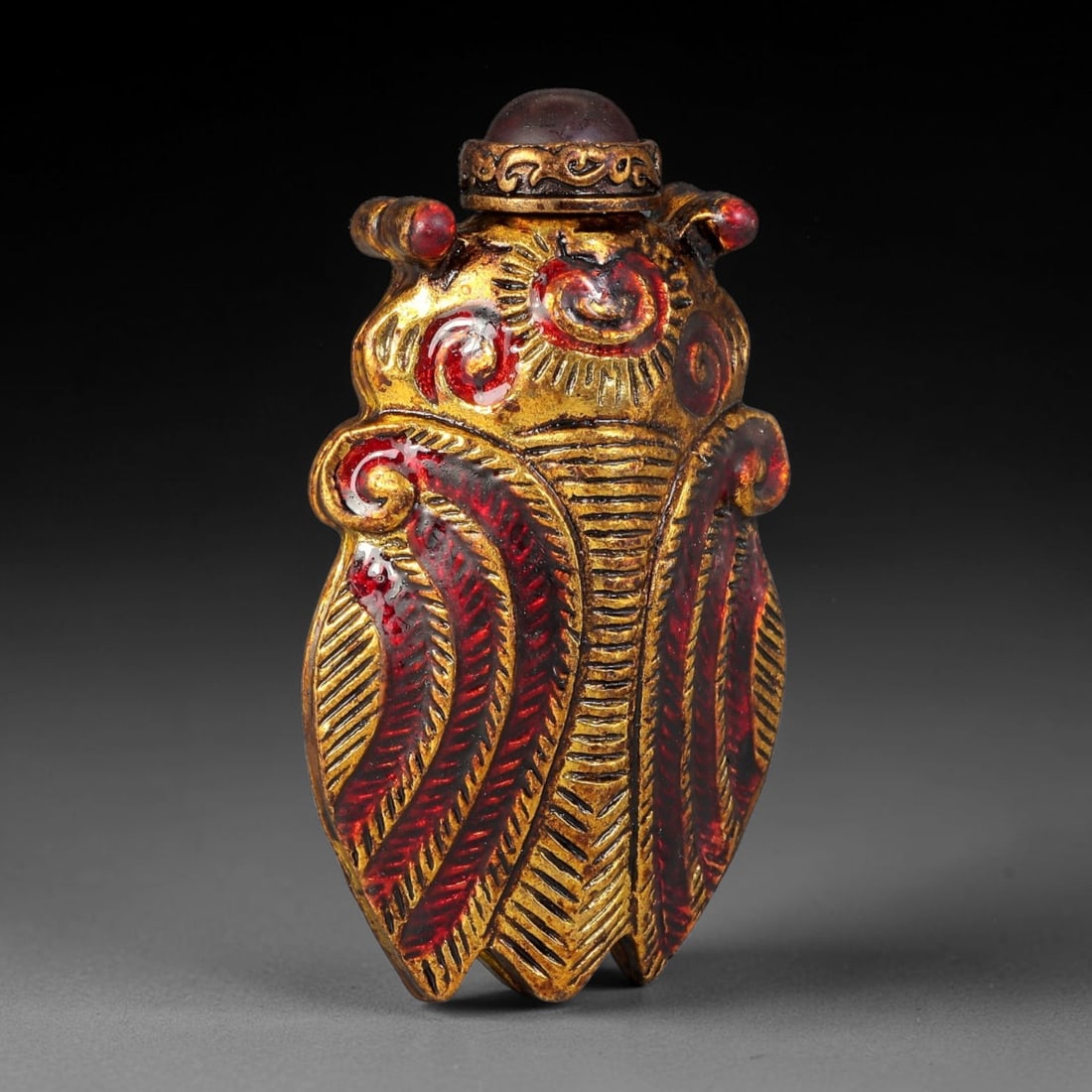 A Chinese Gilt Copper Alloy Cicada Form Snuff Bottle, 6AX: Figural snuff bottle crafted from gilt copper alloy, modelled as a cicada with fine incised wing detailing accented with red enamel scrollwork and linear texture. The ornate scrolling metal collar hol
