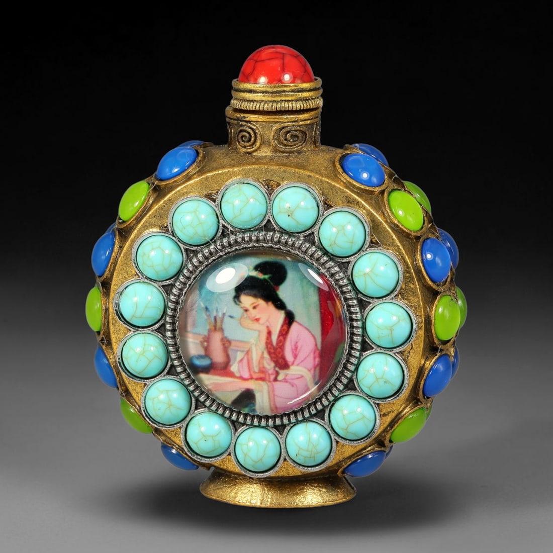 A Chinese Gilt Copper Alloy Inset Painted Panel Snuff Bottle, 36AV: Modelled in gilt copper alloy with a flattened circular form, the snuff bottle features raised scrollwork at the neck and a red simulated coral cabochon stopper. Each face has a central domed painted 