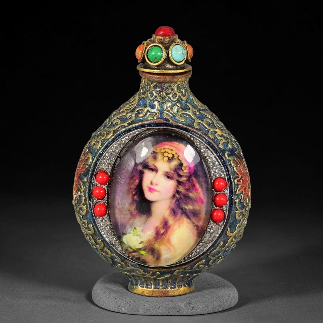 A Chinese Gilt Metal Enamel Snuff Bottle with European Portrait Inset Panels, 38AV: Globular flattened snuff bottle made in gilt metal with deep blue enamel and raised gilt scrolling patterns across the body, fitted with a stopper set with simulated coral, turquoise and orange caboch