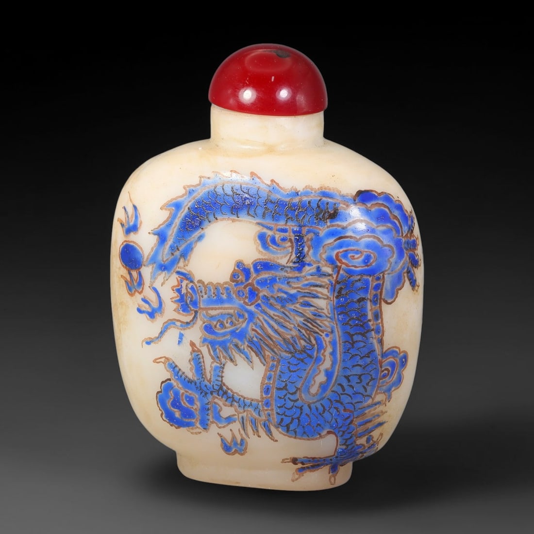 A Chinese White Glass Enamel Dragon and Phoenix Snuff Bottle, 93AL: Opaque white glass snuff bottle decorated on opposing sides with blue enamel dragon and phoenix motifs outlined in brown pigment. One face features a coiled dragon chasing the flaming pearl amid styli
