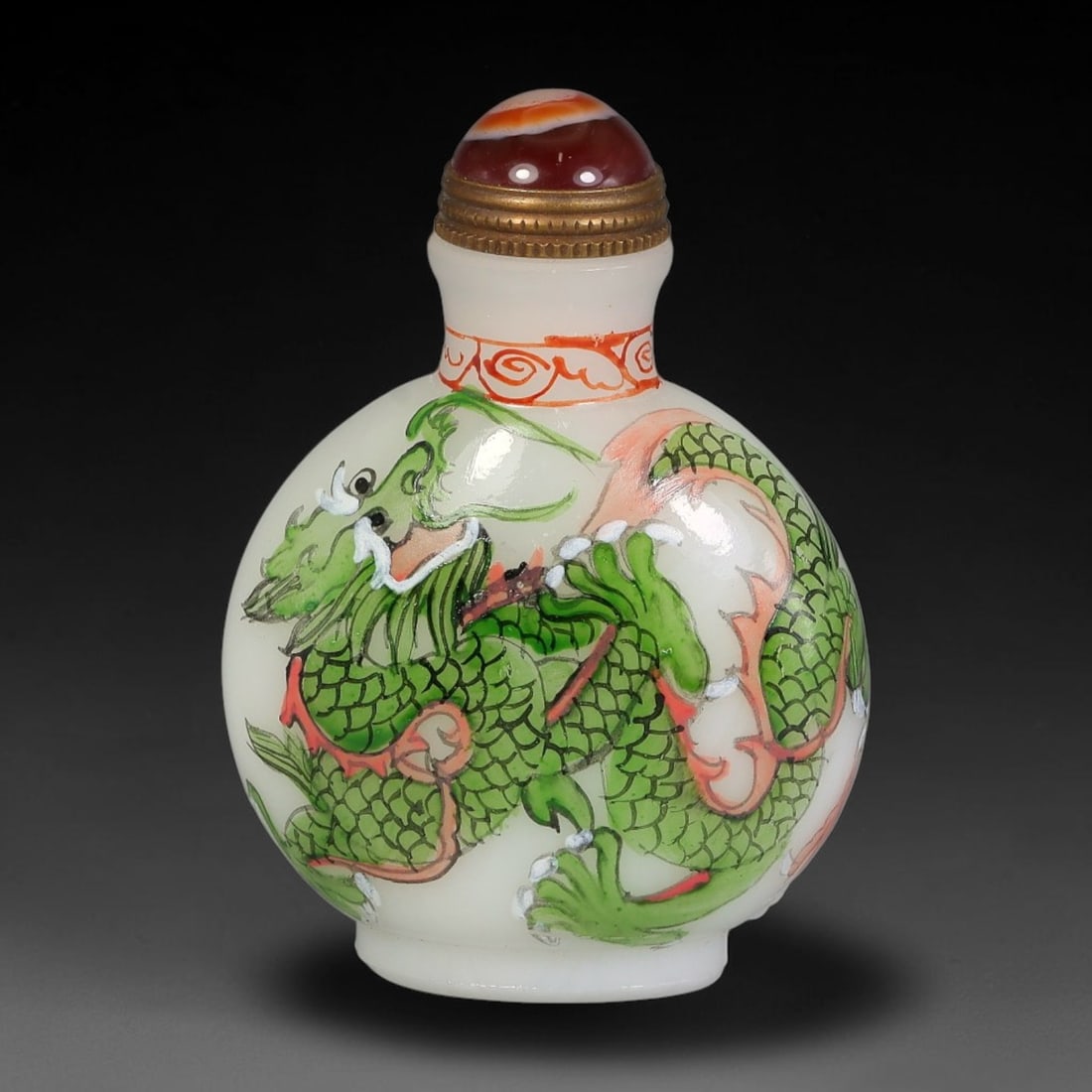 A Chinese White Glass Enamel Painted Dragon Snuff Bottle, 11AV: Globular opaque white glass snuff bottle decorated with opposing enamel dragon motifs. One side features a green-scaled dragon with red mane and claws, the reverse a reddish-brown scaled dragon amid s
