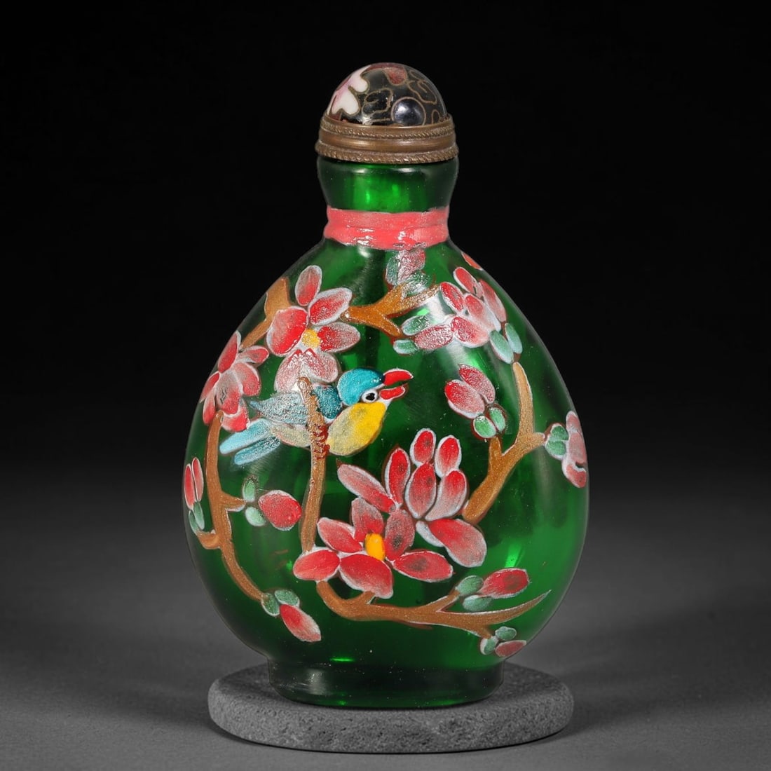A Chinese Emerald Green Glass Enamel Bird and Blossom Snuff Bottle, 51AV: Pear-shaped translucent emerald green glass snuff bottle decorated with polychrome enamel depicting a colourful bird perched among blossoming branches. A thin red band wraps around the neck, fitted wi