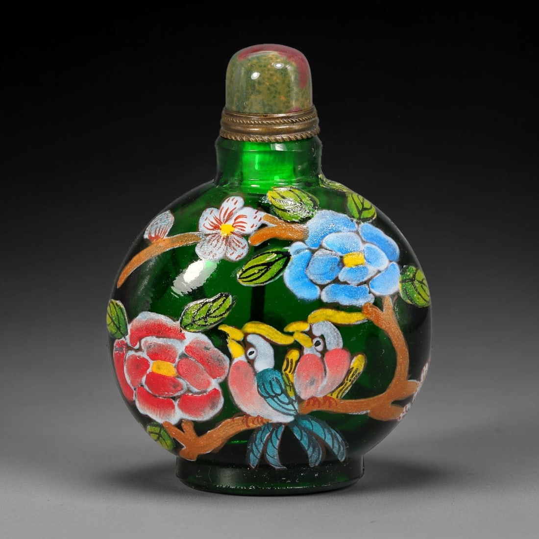 A Chinese Green Glass Enamel Birds and Blossoms Snuff Bottle, 44AV: Globular translucent emerald green glass snuff bottle decorated in vibrant polychrome enamel depicting two birds perched among flowering branches with multi-coloured blooms and foliage. The neck is fi