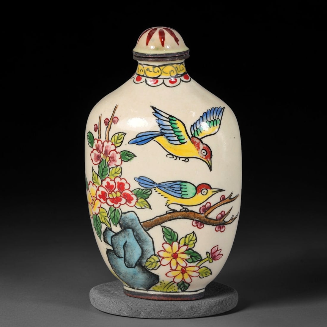 A Chinese Bronze Enamel Two Birds and Flower Snuff Bottle, 81AV: Oblong bronze snuff bottle decorated in painted enamel upon a creamy off-white ground, depicting two colourful birds among flowering branches with rockwork and foliage. The neck is ornamented with yel