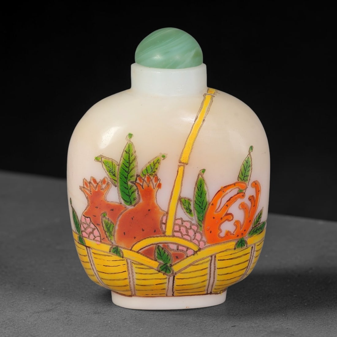 A Chinese White Glass Enamel Fruit Basket Snuff Bottle, 94AL: Ovoid opaque white glass snuff bottle painted in colourful enamel depicting a woven yellow basket filled with pomegranates and finger citron, symbolising abundance and blessing. Naturalistic green fol