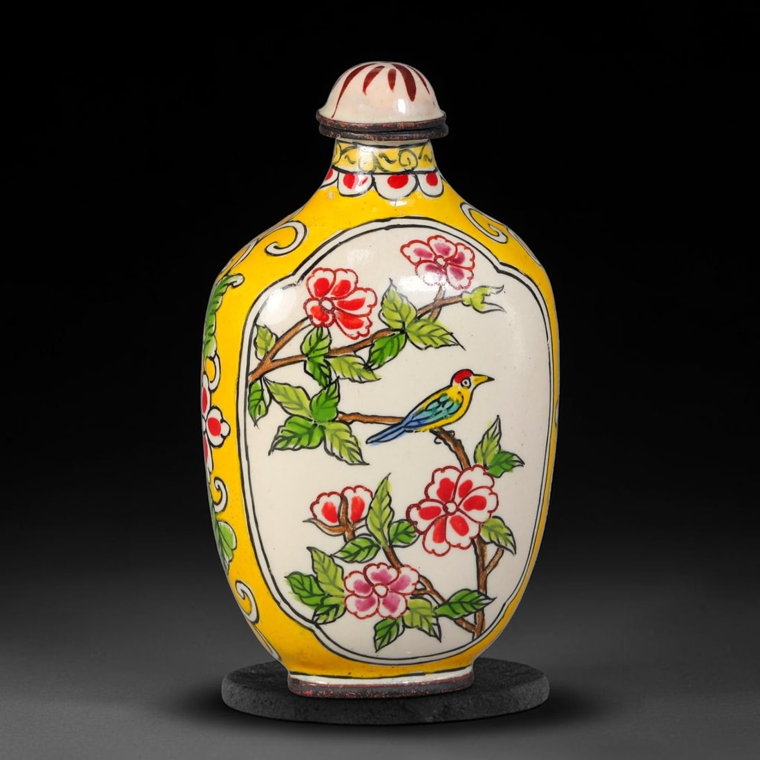 A Chinese Bronze Enamel Bird and Blossom Snuff Bottle, 100AV: Oblong bronze snuff bottle decorated in painted enamel, with a central white reserved panel showing a colourful songbird perched on flowering branches. The surrounding exterior features a vivid yellow