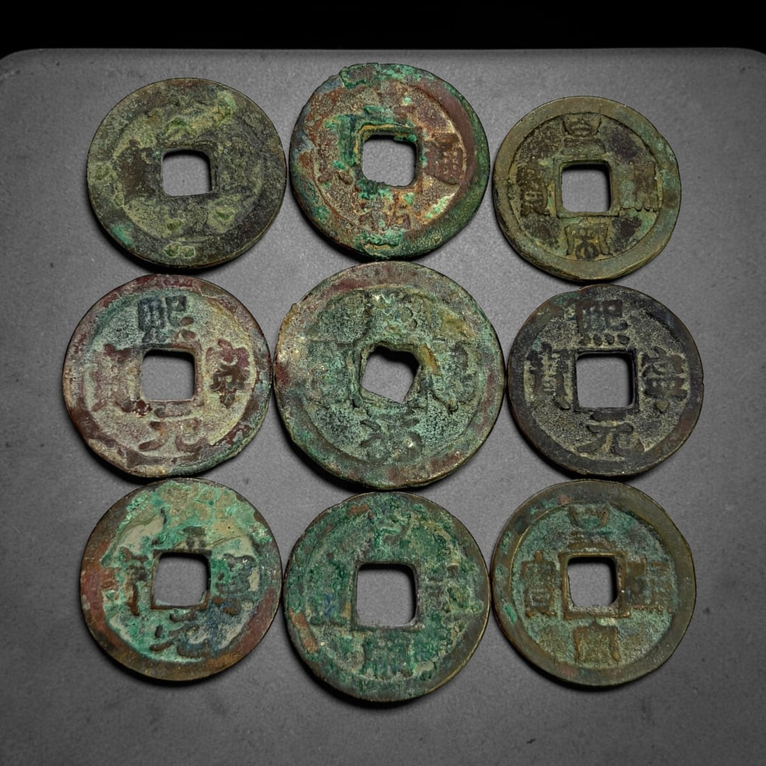 Lot of 9 Ancient Chinese Song Dynasty Bronze Cash Coins, 7BD: A collection of nine bronze square-hole cash coins from the Song dynasty. Each coin bears inscribed coinage characters on the obverse, with varied patina, verdigris and earthen encrustation accumulate