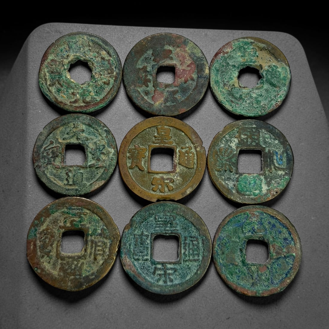 Lot of 9 Ancient Chinese Song Dynasty Bronze Cash Coins, 8BD: A collection of nine bronze square-hole cash coins from the Song dynasty. Each coin bears inscribed coinage characters on the obverse, with varied patina, verdigris and earthen encrustation accumulate