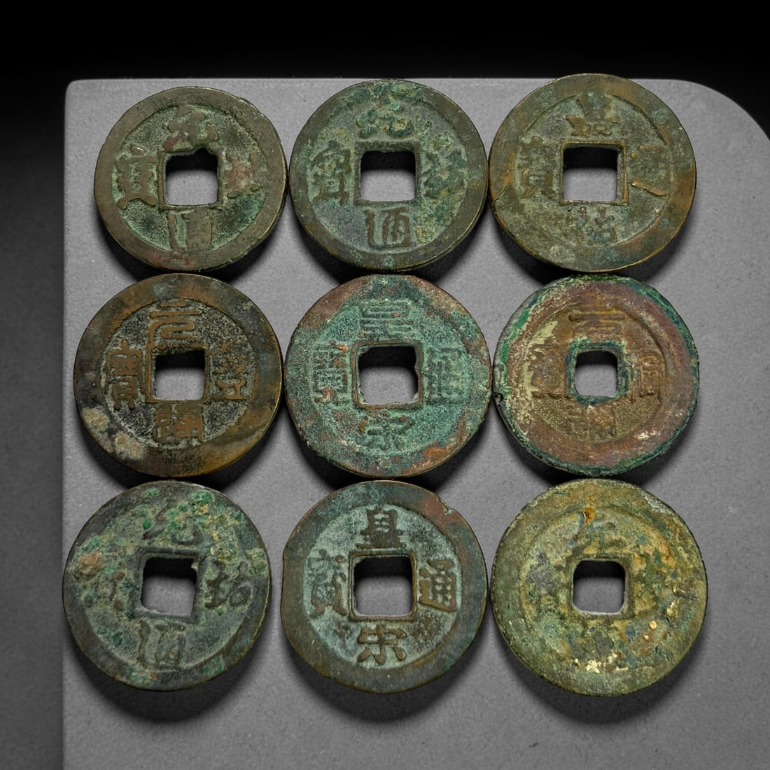 Lot of 9 Ancient Chinese Song Dynasty Bronze Cash Coins, 10BD: A collection of nine bronze square-hole cash coins from the Song dynasty. Each coin bears inscribed coinage characters on the obverse, with varied patina, verdigris and earthen encrustation accumulate
