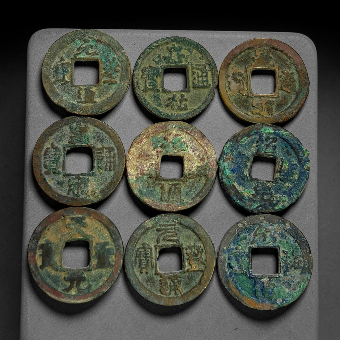Lot of 9 Ancient Chinese Song Dynasty Bronze Cash Coins, 40BD: A collection of nine bronze square-hole cash coins from the Song dynasty. Each coin bears inscribed coinage characters on the obverse, with varied patina, verdigris and earthen encrustation accumulate