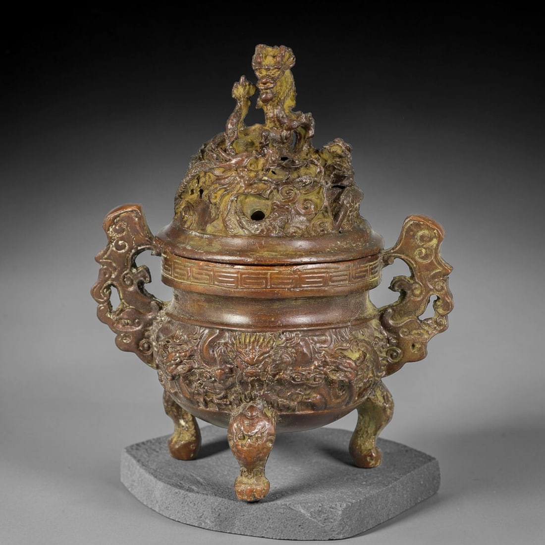 A Chinese Bronze Dragon Decorated Tripod Censer with Openwork Cover, 8AX: Cast bronze tripod censer with elaborate dragon ornamentation. The domed openwork cover is crowned by a prominent dragon finial with surrounding coiled dragons for smoke release. The rounded body is m