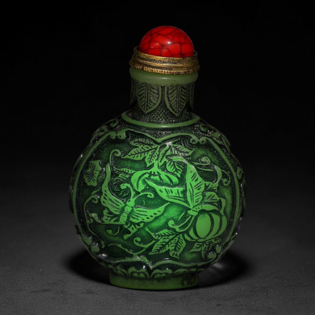 A Chinese Phosphorescent Green Relief Carved Bat, Peach and Butterfly Snuff Bottle, 89AV: Globular phosphorescent green snuff bottle, the material glows neon in the dark when illuminated by torch light, deeply relief-carved with butterfly, melon and foliage on one face, bats and longevity 