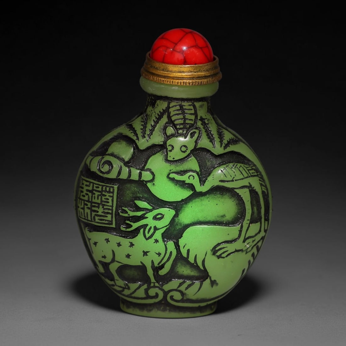 A Chinese Phosphorescent Green Relief Carved Deer and Crane Snuff Bottle, 84AV: Globular phosphorescent green snuff bottle, the material glows neon in the dark when illuminated by torch light, deeply relief-carved with deer, crane and bat motifs on one side alongside a seal mark,