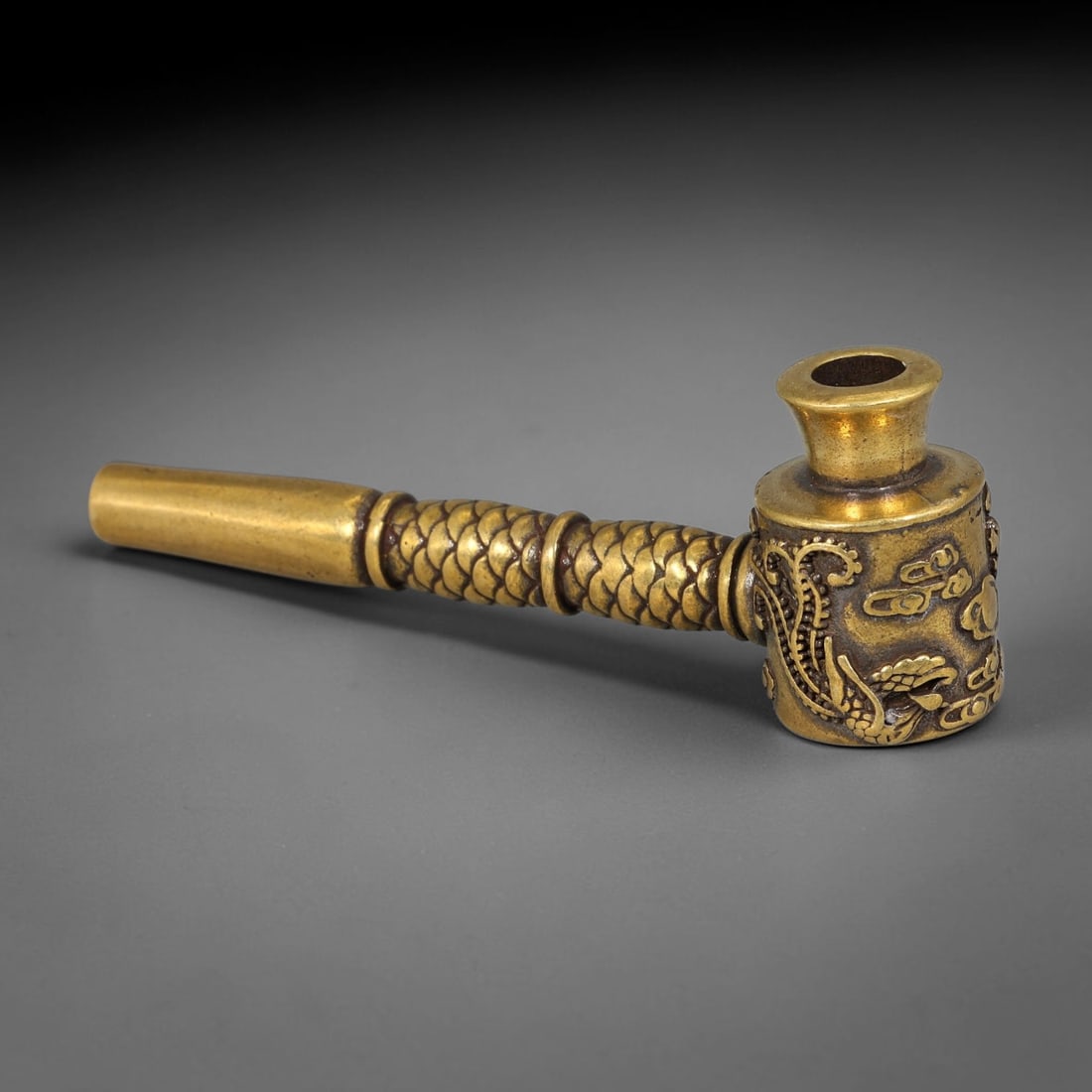 A Chinese Gilt Bronze Dragon Smoking Pipe, 83AX: Cast gilt bronze pipe with straight stem and cylindrical bowl. The bowl is decorated in relief with a dragon motif interspersed with cloud patterns. The stem bears raised scale detailing separated by 