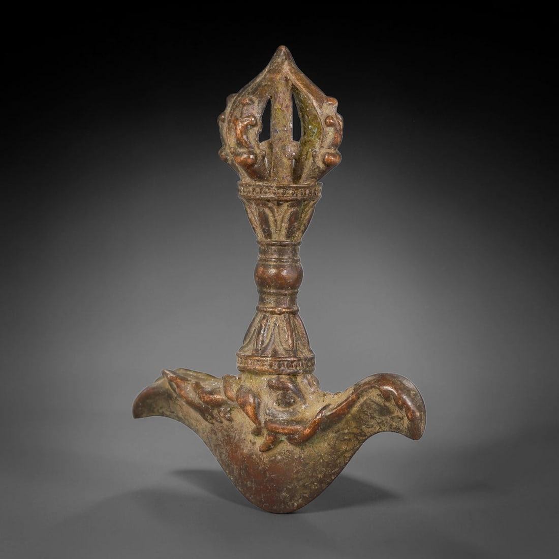 A Tibetan Bronze Kartika Ritual Implement with Vajra Finial, 40AX: Cast bronze Tibetan ritual kartika knife topped with an openwork vajra finial, detailed with foliate mouldings and raised decorative bands along the tapering stem. The curved blade is adorned with emb