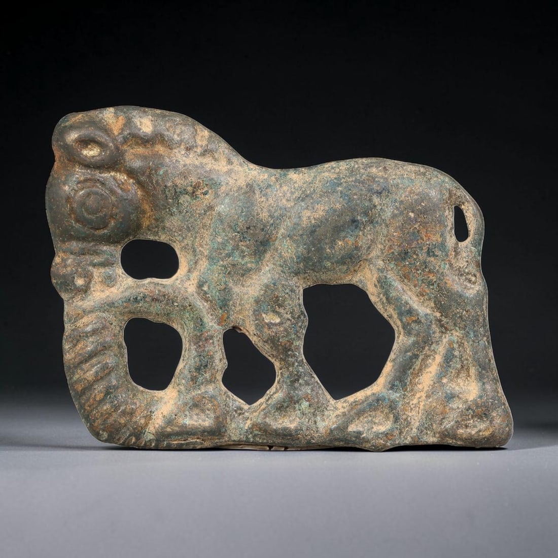 A Mongolian Steppe Bronze Openwork Animal Plaque, 65BD: Flat cast bronze openwork plaque depicting a stylized standing animal figure with incised mane and facial detailing, pierced negative space cutouts throughout the composition. The bronze bears heavy a