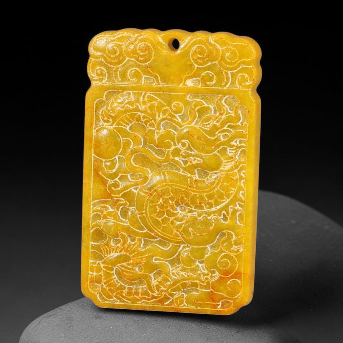 A Chinese Carved Yellow Jade Dragon Plaque Pendant, 25BD: Rectangular yellow jade plaque with cloud-scroll ornamentation at the upper pierced suspension section. The main face is incised and relief decorated with a sinuous dragon chasing a flaming pearl amid