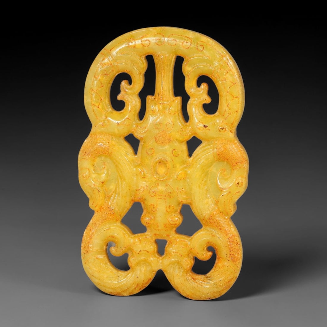 A Chinese Openwork Yellow Jade Symmetrical Twin Dragon Plaque Pendant, 30BD: Symmetrical openwork yellow jade plaque formed by interlocking twin dragon motifs arranged around a central stylized beast element. Pierced voids separate the curling bodies, with fine incised lines d