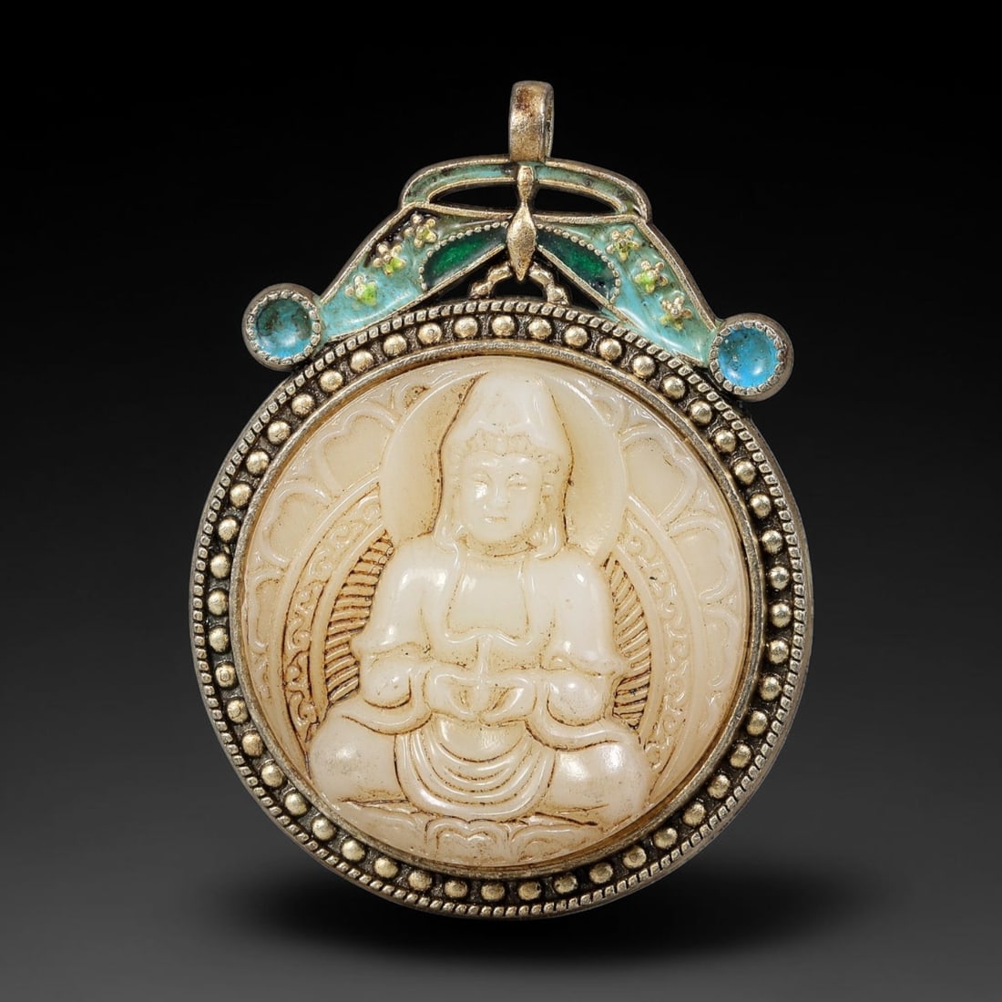 A Chinese Enameled Metal Mounted Carved Guanyin Double-Sided Pendant, 4BF: Double-sided circular pendant set with a carved pale stone plaque depicting seated Guanyin on one face within a beaded metal frame. The reverse features raised enamel decoration of a guardian lion set