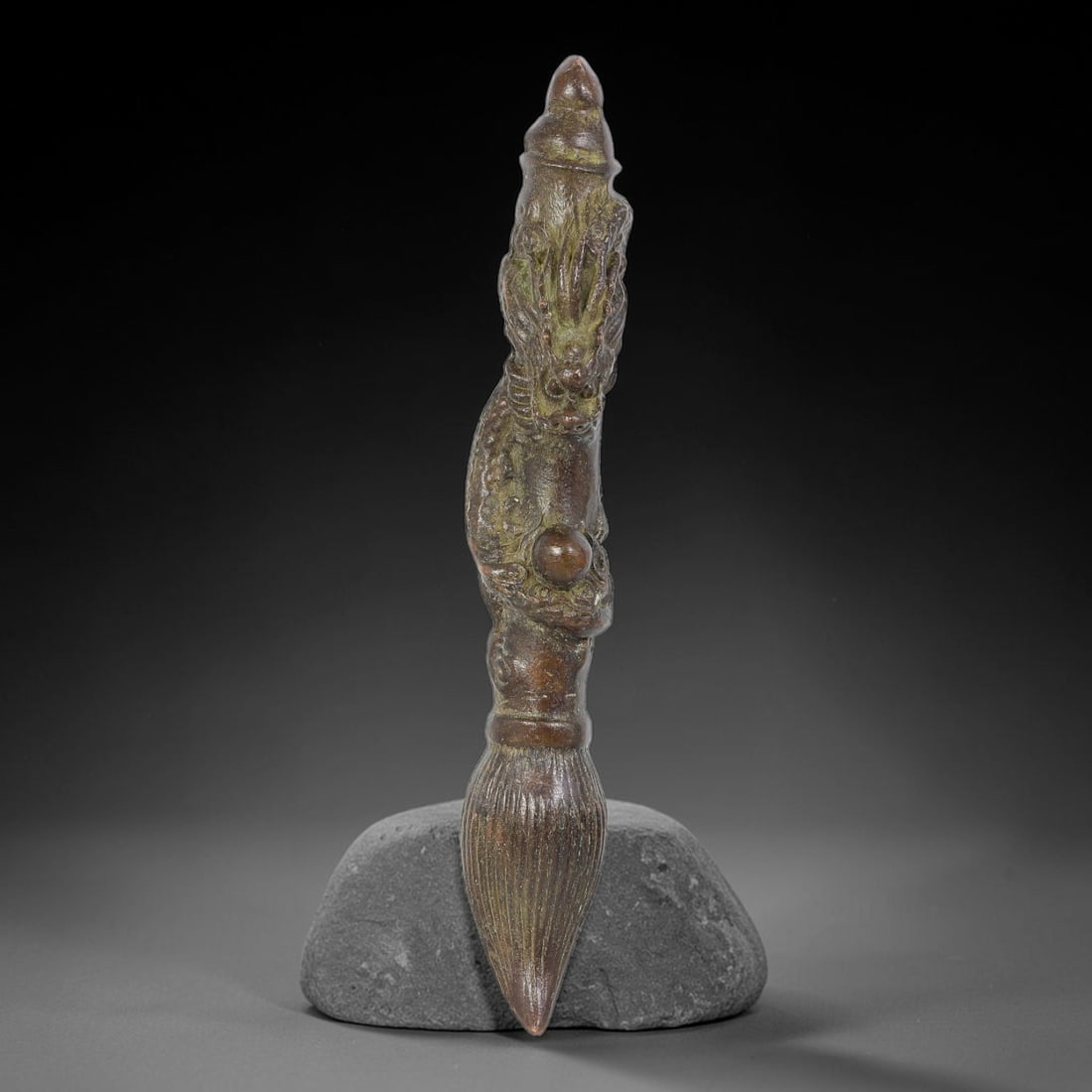 A Chinese Bronze Dragon Wrapped Writing Brush Amulet, 72AX: Cast bronze amulet modelled in the form of a traditional writing brush, with a relief dragon coiled along the shaft clutching a pearl. The brush tip is detailed with fine vertical striations, and the 