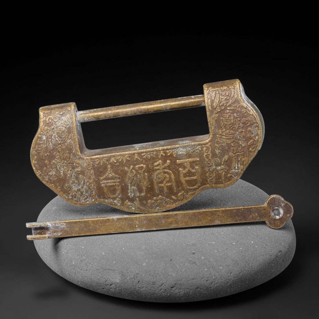 A Chinese Bronze Padlock with Inscription, 69AX: Traditional Chinese bronze cloud-form padlock complete with its original key. The lock face is cast with Chinese characters and flanking figural motifs, retaining an aged golden-brown patina with mino