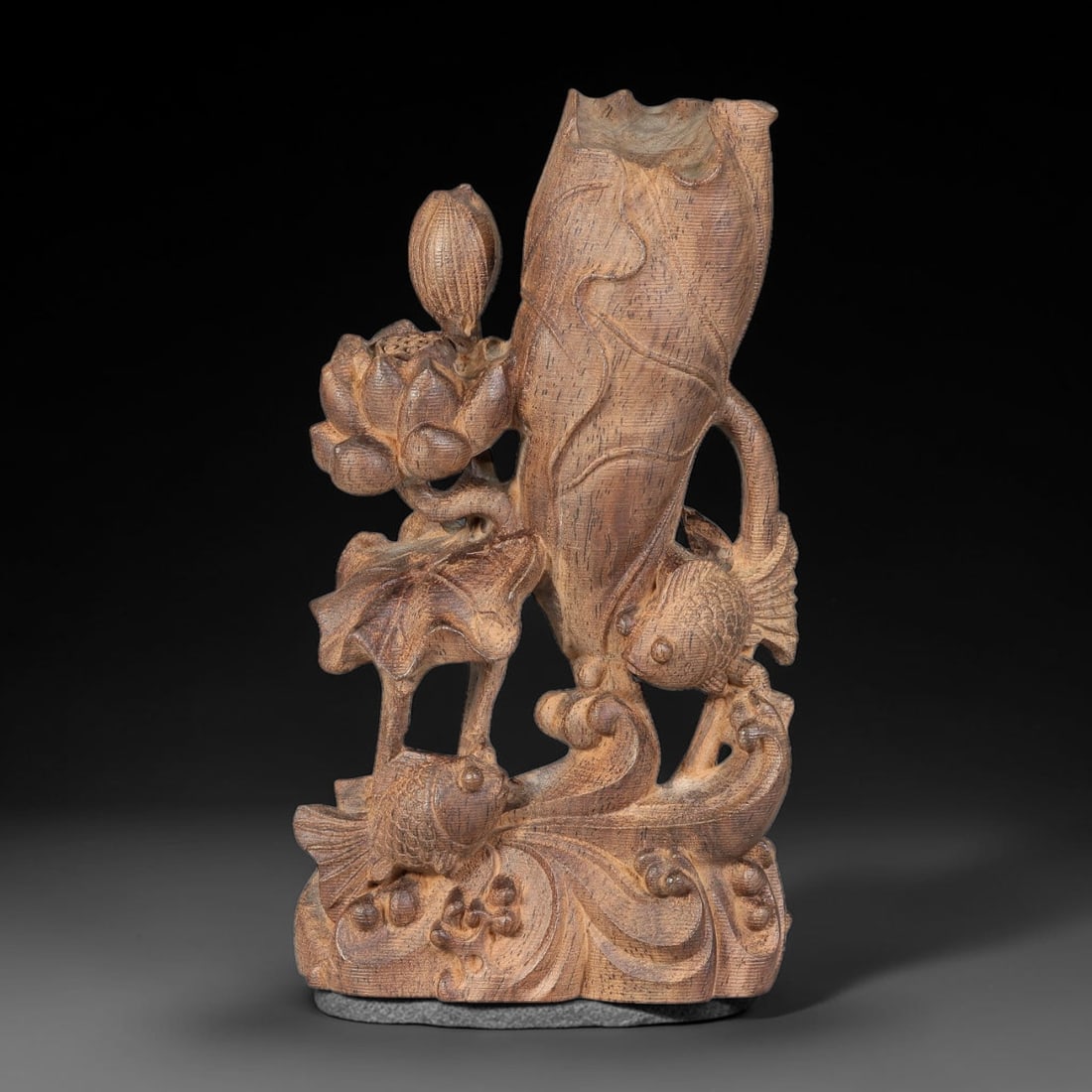 A Chinese Agar Wood Carved Sculpture with Lotus and Twin Fish Motif, 89BD: Openwork agar wood sculpture intricately carved with interwoven lotus blooms, seed pod, curling foliage and twin fish rising among stylized wave forms. A hollowed lotus leaf forms a vase opening at th