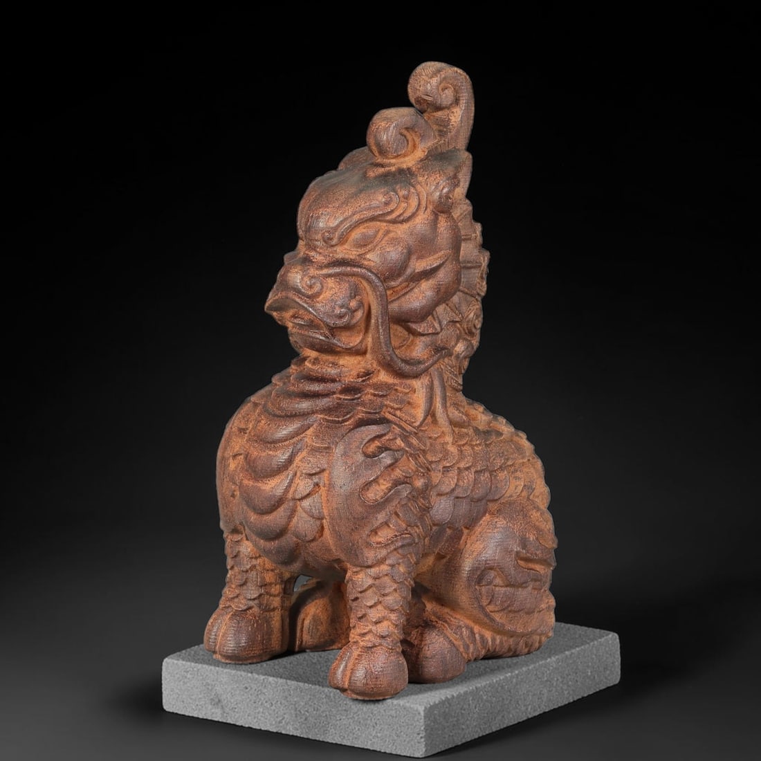 A Chinese Agarwood Carved Qilin Sculpture, 88BD: Solid agarwood carving depicting a seated qilin, finely detailed with curled horns, flowing whiskers, layered scale work across the body and limbs. The natural wood grain and textured surface are pres