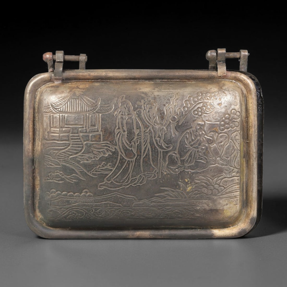 A Chinese Engraved Rectangular Metal Lidded Box, 49BD: Rectangular hinged lidded box with engraved figural landscape scene featuring scholars, pavilion and foliage on the exterior lid. The reverse bears two stamped seal marks, and the interior surface is 