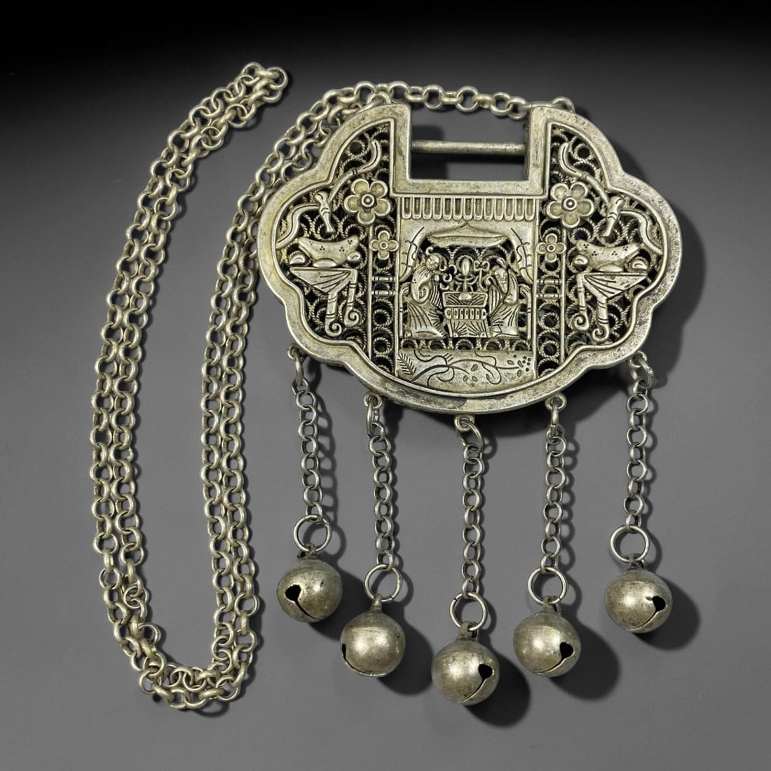 A Chinese Filigree German Silver Hundred Family Lock Pendant Necklace, 90BD: Filigree German silver ruyi-shaped lock pendant, the front finely worked with a pavilion figural scene framed by floral and decorative elements. The reverse displays openwork filigree ground inset wit
