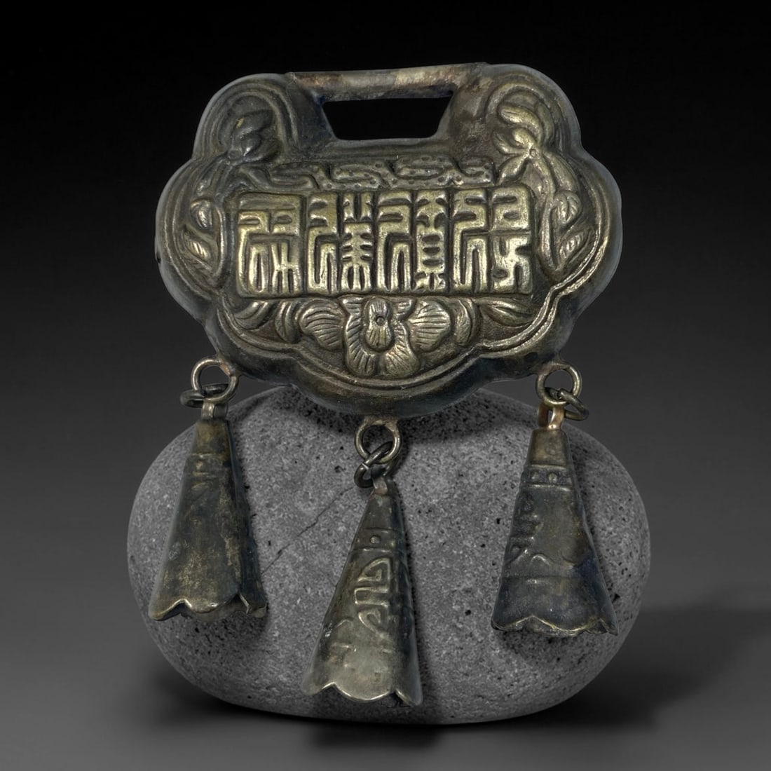 A Chinese Vintage Silver Ruyi Lock Pendant with Cone Bells, 97BD: Vintage silver ruyi-shaped lock pendant with an aged dark patina. One side displays embossed seal script characters above a floral motif, flanked by decorative scrollwork. The reverse features repouss