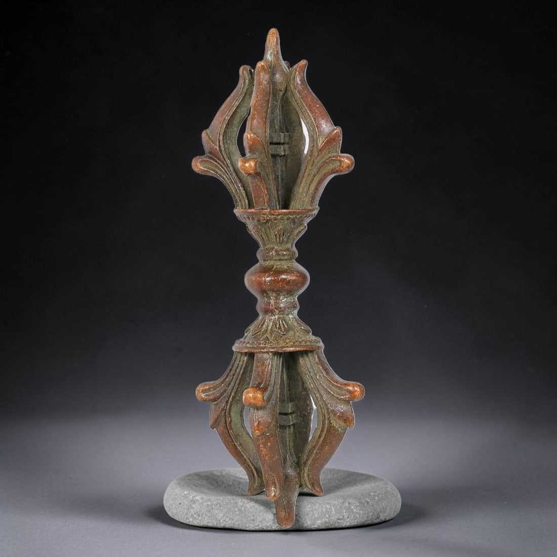A Tibetan Bronze Double Vajra Ritual Implement, 71AX: Cast bronze double vajra featuring symmetrical multi-pronged upper and lower sections with flaring petal-shaped prongs, joined by a knopped central baluster stem with fine decorative moulding. The pie