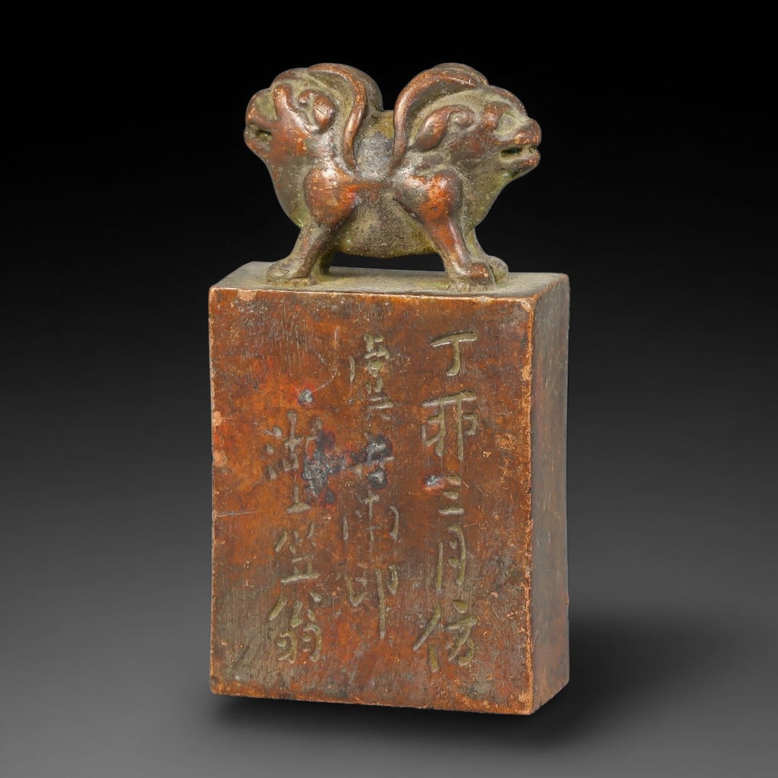 A Chinese Bronze Double-Headed Mythical Beast Rectangular Seal, 30AX: Cast bronze rectangular seal surmounted by a finely modelled double-headed mythical beast finial with curled decorative details. The vertical sides of the seal block bear incised calligraphic inscript