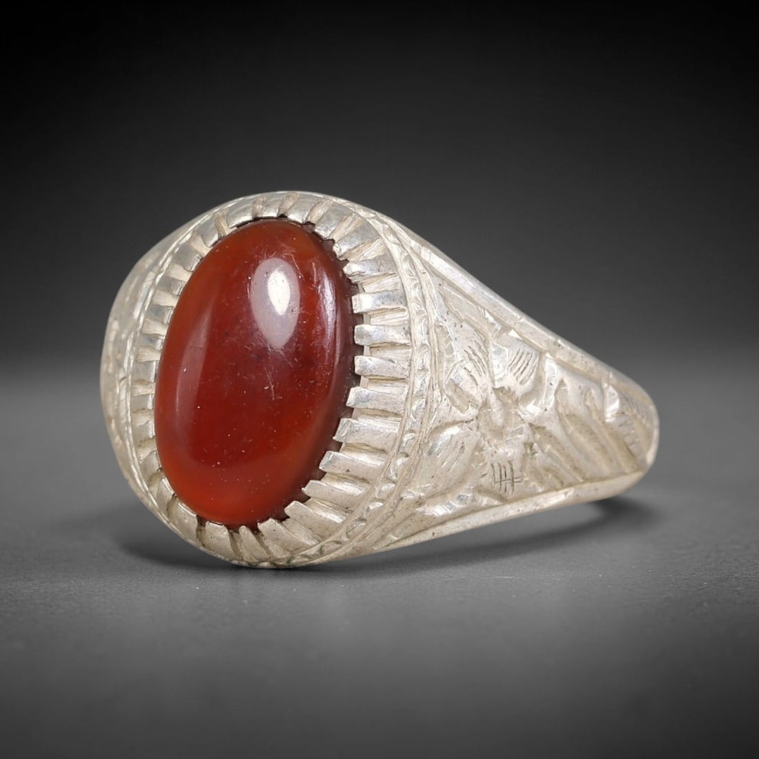 Antique Ottoman Garnet Radiating Incised Bezel Floral Engraved Silver Ring, 24AL: Silver ring of the Ottoman period set with an oval cabochon garnet secured within a radiating incised bezel. The ring shoulders carry detailed floral engraved decoration. Marked with hallmark 90. Ring
