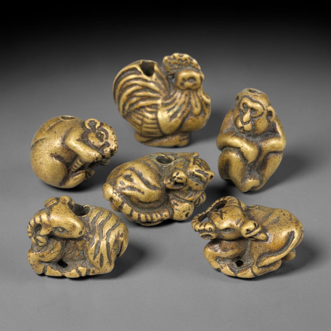 Lot of Six Chinese Bronze Zodiac Animal Beads, 73BD: Group of six cast bronze zodiac animal beads, each individually sculpted with a drilled perforation for threading. The set features rat, ox, tiger, ram, monkey and rooster motifs, finished with a warm