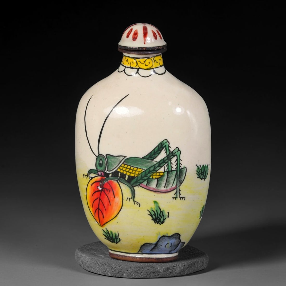 A Chinese Bronze Enamel Grasshopper Snuff Bottle, 99AV: Oblong bronze snuff bottle with painted enamel decoration, depicting a large grasshopper resting upon a red leaf amid tufts of grass and rockwork, with a creamy white body and yellow ground accents. T
