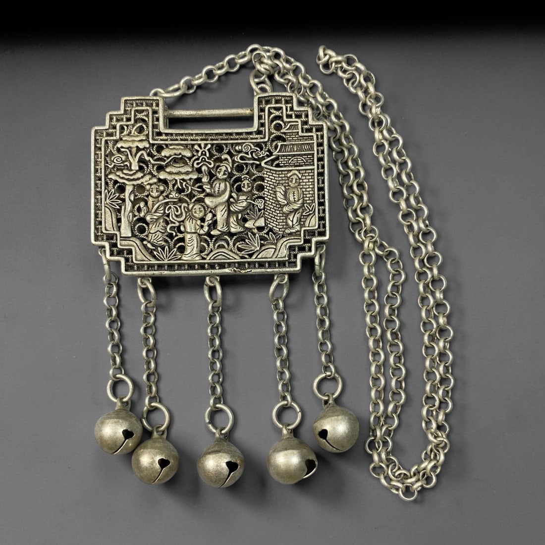 A Chinese German Silver Rectangular Figural Lock Pendant Necklace, 95BD: German silver rectangular lock pendant with stepped geometric borders. The obverse displays elaborate openwork relief depicting a traditional Chinese garden scene with multiple figures amidst foliage 