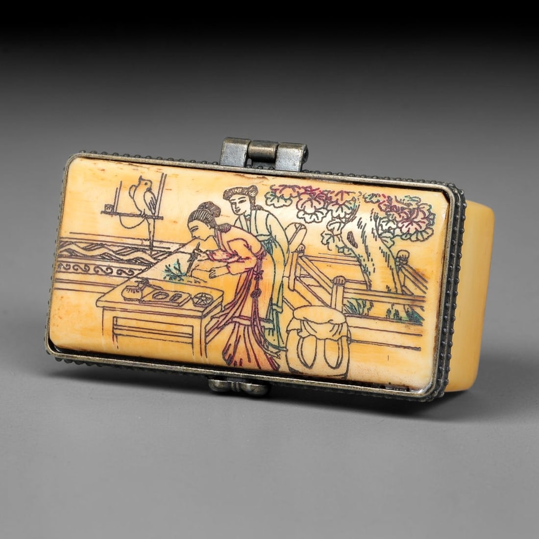 A Chinese Antique Engraved Bone Trinket Box with Ladies, Goldfish and Garden Motifs, 50BT: This rectangular bone trinket box is decorated on the lid with finely engraved and coloured figures of two ladies in a garden setting, accompanied by plants, a bird, and architectural details. The bod
