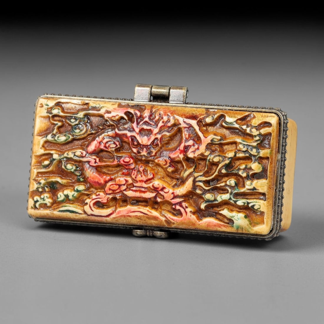 A Chinese Antique Carved Bone Trinket Box with Dragon and Orchid Motifs, 51BT: This rectangular bone trinket box features an ornate carved lid decorated with a vivid dragon amid scrolling clouds and floral details, highlighted in red, green, and amber tones. The body is fitted w