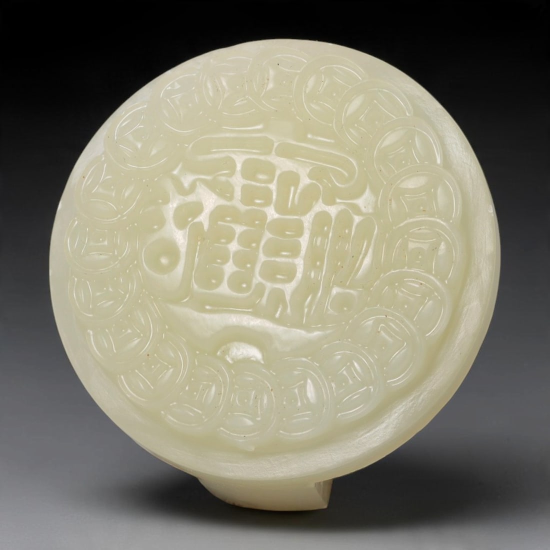 A Chinese Natural Qinghai Nephrite Jade Belt Buckle, 21AT: This circular belt buckle is carved from natural Qinghai nephrite jade, with soft pale cream tones accented by warm peach and orange russet patches across the stone surface. The front face features ra