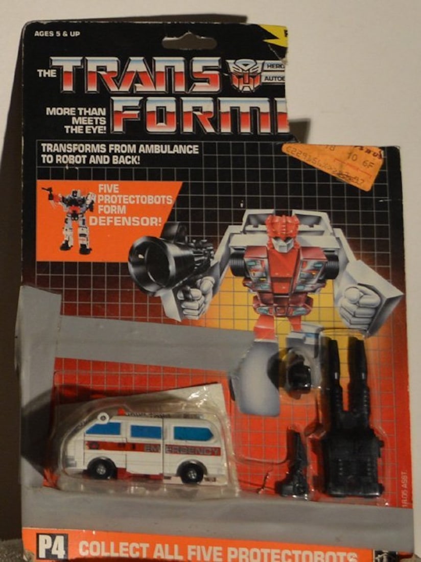 THE TRANSFORMERS "FIRST AID": THE TRANSFORMERS "FIRST AID".TRANSFORMS FROM AMBULANCE TO ROBOT AND BACK.FIVE PROTECTORBOTS FORM DEFENSOR!.THIS ITEM WAS TAPED TO THE ORIGINAL PACKAGING (SEE PICTURES).COMPLETE AND INTACT