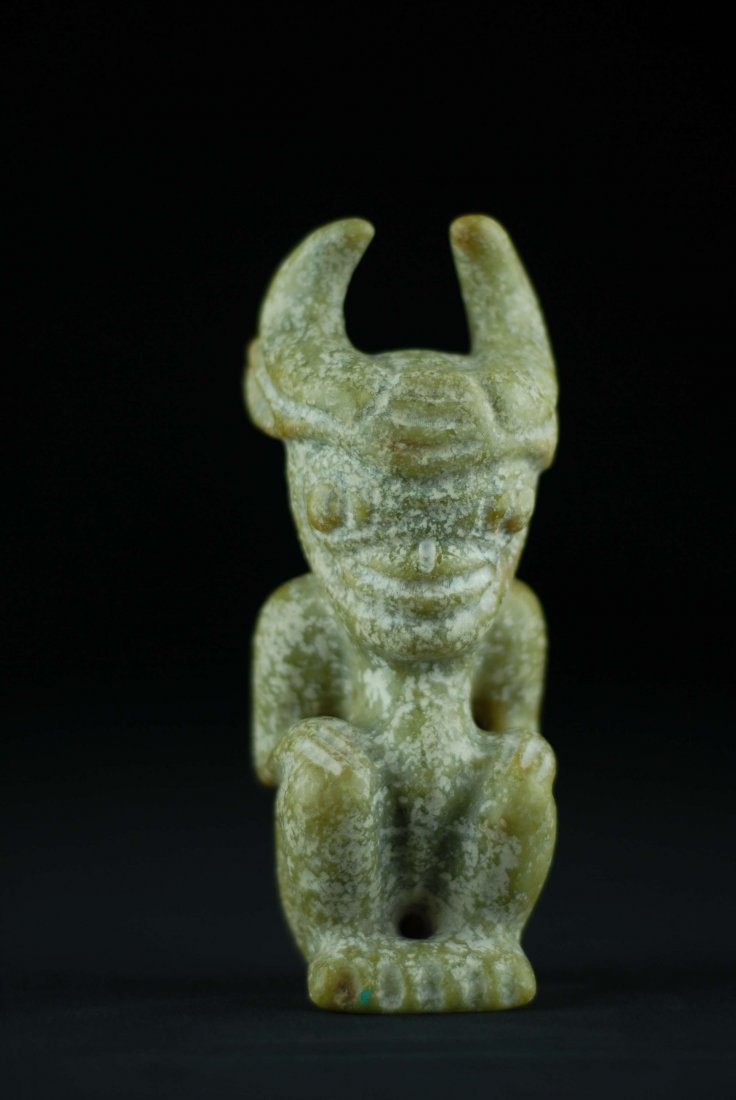 A HONG SHAN CULTURE CALCIFIED JADE SEATED FIGURE: A HONG SHAN CULTURE CALCIFIED JADE SEATED SUN GOD, hand carved, mottled green jade figure resembling a horned animal with bulbous eyes, pulled back ears. Dimensions, Height: 7", Width: 2.5" and Depth: