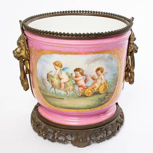 1800s Sevres Pink Porcelain Cherub Jardiniere Cache: 19th Century Sevres French Porcelain Potted Plant Holder Features Hand Painted Cherub Children Scene Gold Gilt Footing and Frame Measures approx. 10" tall and 9.5" diameter.