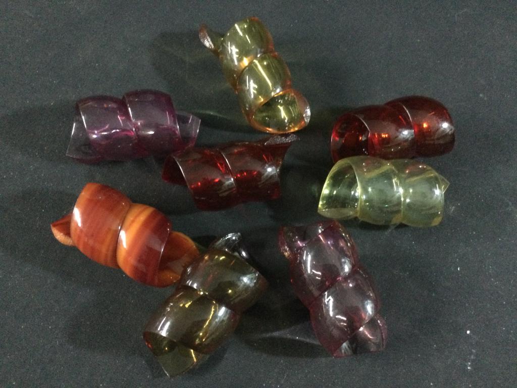 Vintage Lucite Napkin Rings: Total of 8 in this They range in a variety of colors (red, purple, brown, gold, etc). In good condition & shaped in form of ribbons.