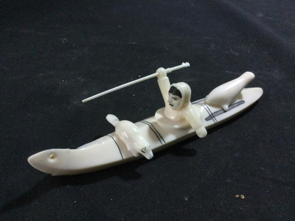Carved Alaskan Ivory: Signed on bottom by artist. Depicts canoe with fisherman catching seals with 2 already on his canoe. Scrimshaw and detail is outstanding. Measures 6"l and in goof condition.