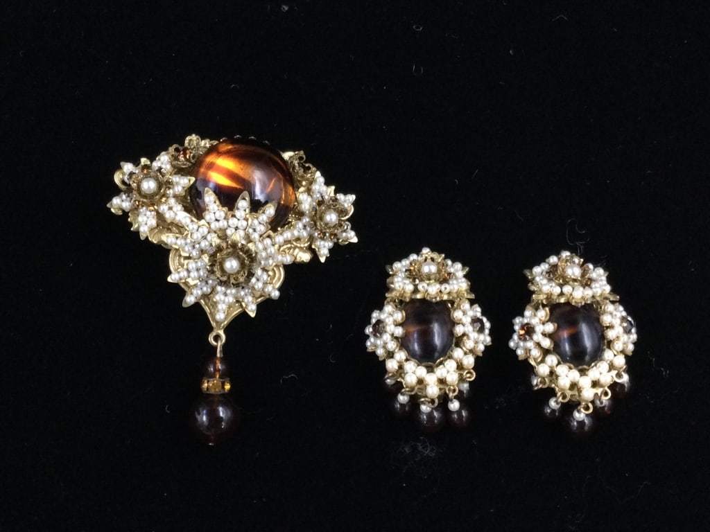 Stanley Naggler NYC: Demi Parure of pin and matching earrings. Dar amber cabochon on pin of approx 1" with drop ball pendant of .47". Earrings has amber dark center and all are surrounded by faux pearls and amber crystals