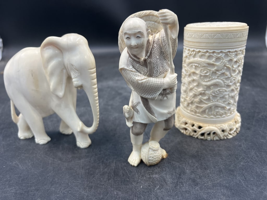 Carved Figures and Animals: Total of 3 pieces There is carved elephant 4 1/4" x 4" without tusk. The other piece is a scrimshaw male fishing with pole broke. He is signed. The last piece is a 4" Brush pot with crack down its sid
